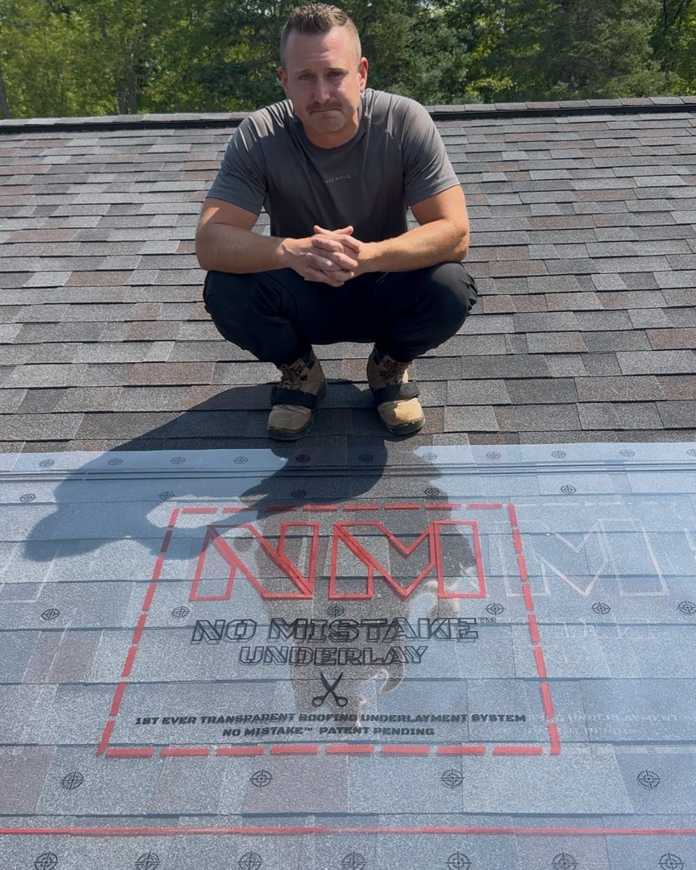 Evan crouched on finished shingles with the transparent underlayment laid over them.